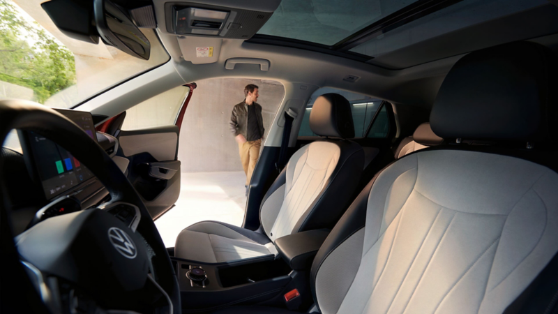 Blick durch die Fahrertür des VW T-Roc auf das Interieur mit hellen Sitzen.