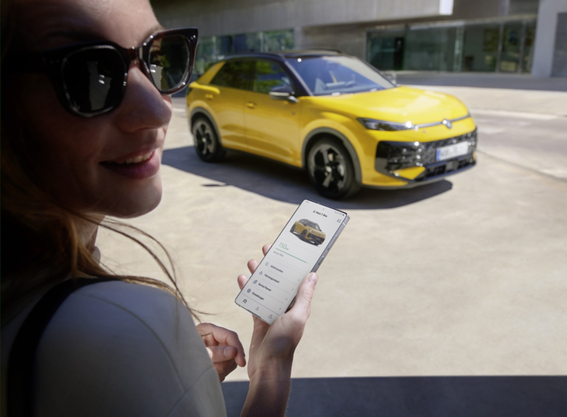 Una mujer utiliza la aplicación VW Connect junto a su VW T-Roc R-Line.