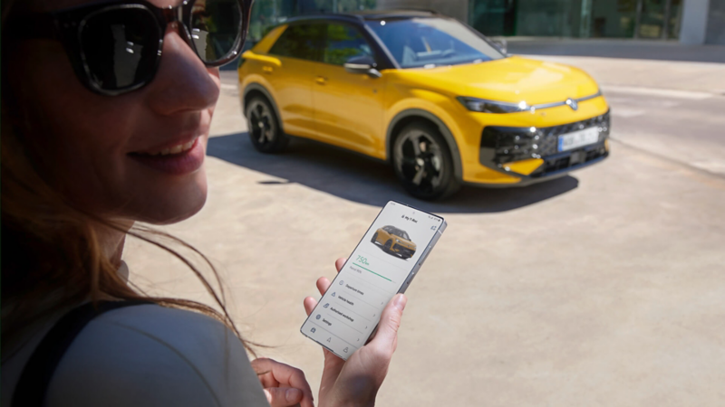 Une femme utilise l’application VW Connect à côté de son VW T-Roc R-Line.