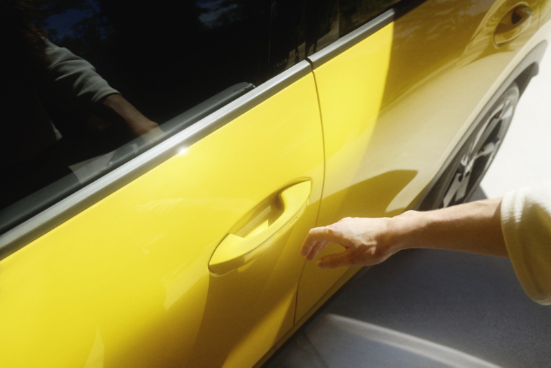 Una mano abre un VW T-Roc R-Line amarillo mediante el sistema Keyless Access.