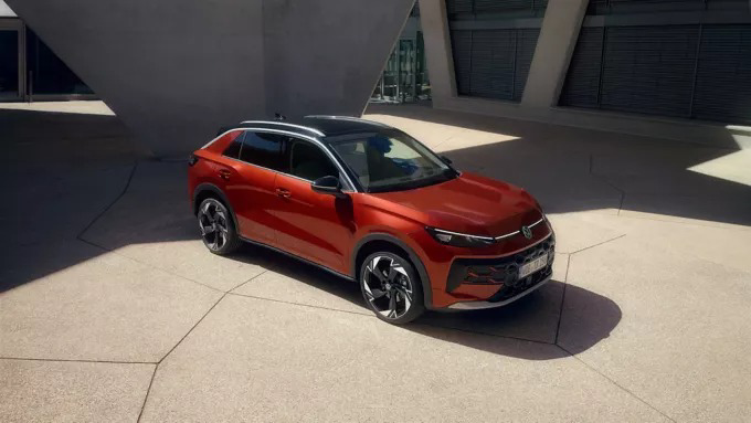 Czerwony VW T-Roc Style stoi przed nowoczesnym budynkiem w promieniach słońca.