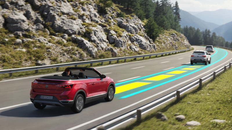 VW T-Roc Cabriolet ENERGY fährt auf einer Bergstraße mit aktivem Travel Assist.