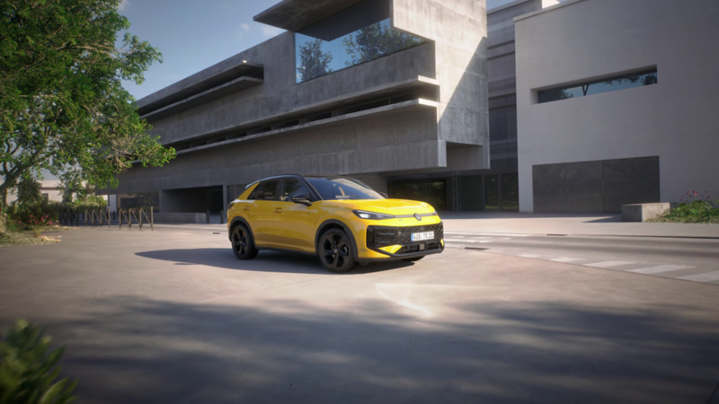 Een gele T-Roc R-Line voor een modern gebouw met betonnen architectuur.
