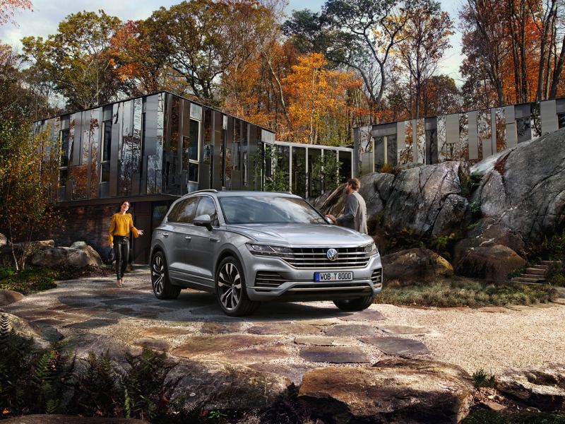 En begagnad Volkswagen Touareg parkerad framför en villa. En man och en kvinna på väg mot bilen.