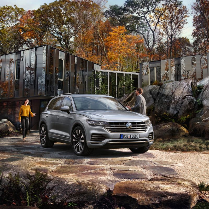 En begagnad Volkswagen Touareg parkerad framför en villa. En man och en kvinna på väg mot bilen.