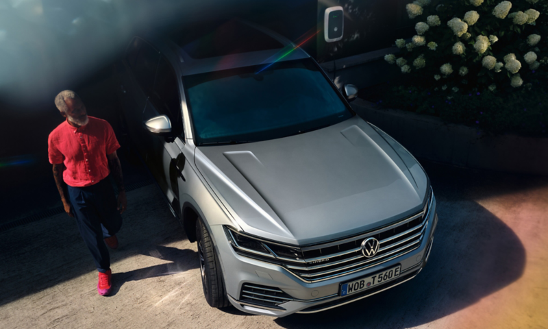 Volkswagen Touareg eHybrid in Silber, Front-Sicht, steht in Einfahrt, Mann geht vorbei