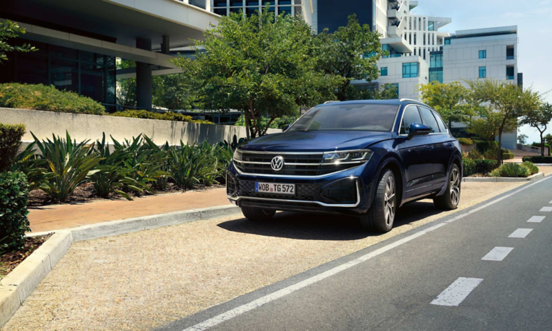 Hombre delante de un Volkswagen Touareg y mujer entrando al coche