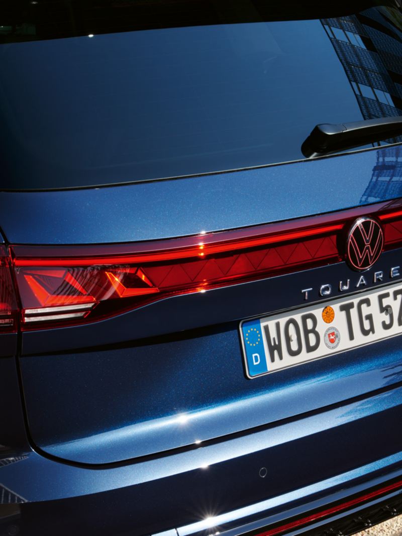Vue de la face arrière de la VW Touareg R-Line avec des feux arrière LED, un bandeau lumineux et le logo VW illuminé.