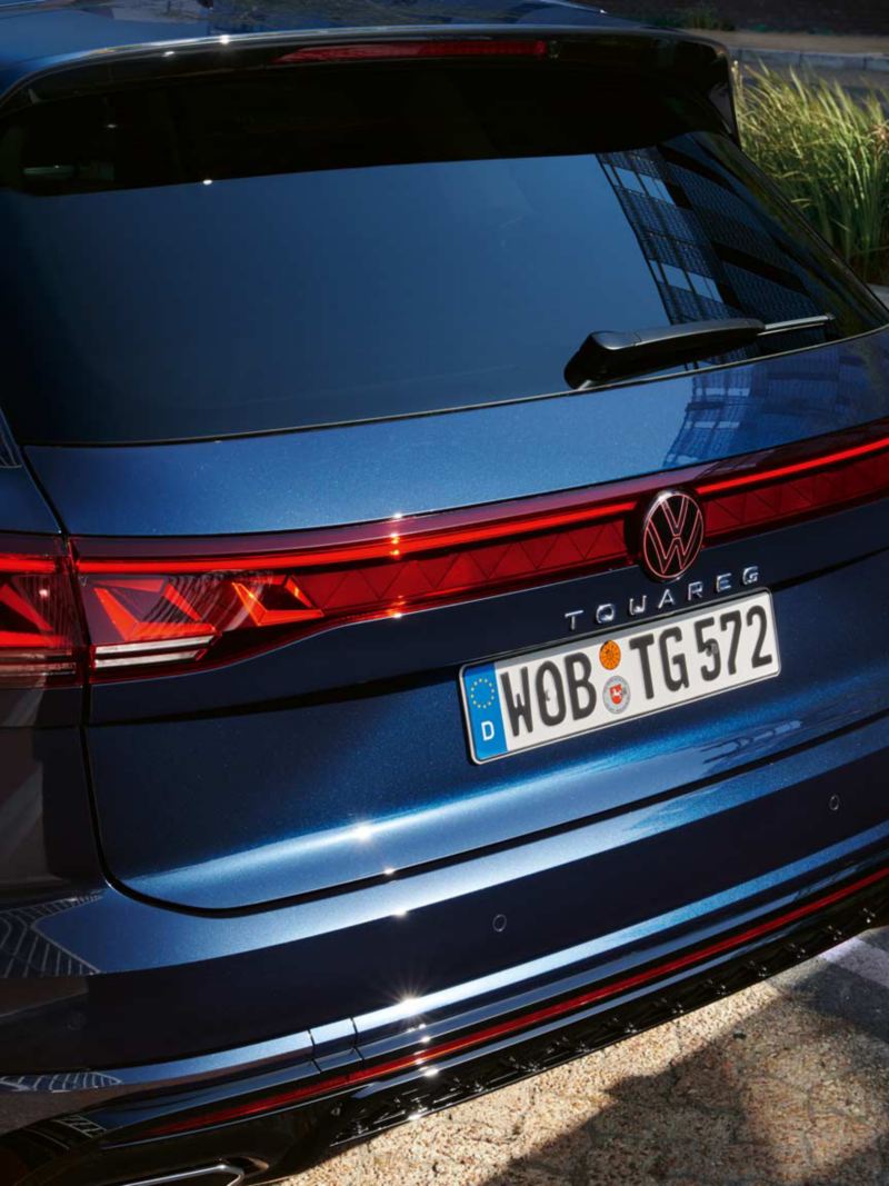 View of the rear of the VW Touareg R-Line with LED tail light clusters, light strip and illuminated VW logo.