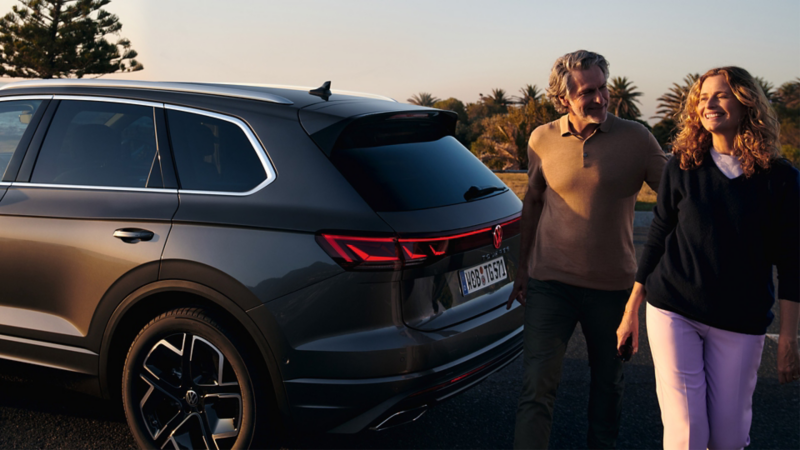 Two people passing the rear of a Touareg