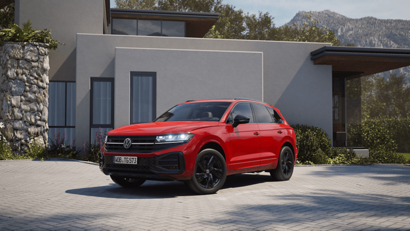 Widok z przodu na bok czerwonego VW Touarega z elementami R-Line „Exterieur Black Style”.