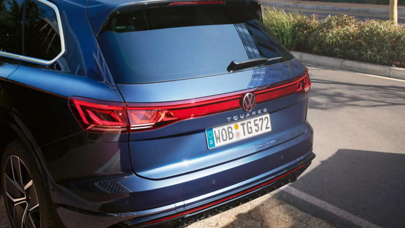 Blick auf das Heck des VW Touareg R-Line mit LED-Rückleuchten, Lichtleiste und illuminiertem VW Logo.