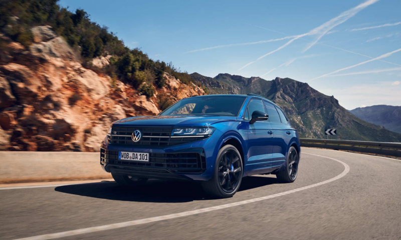 En VW Touareg R eHybrid kör längs en väg kantad av berg