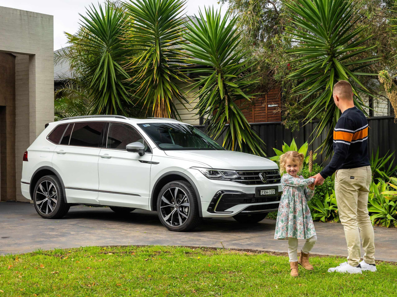 Father and daughter stood next to white VW in drive
