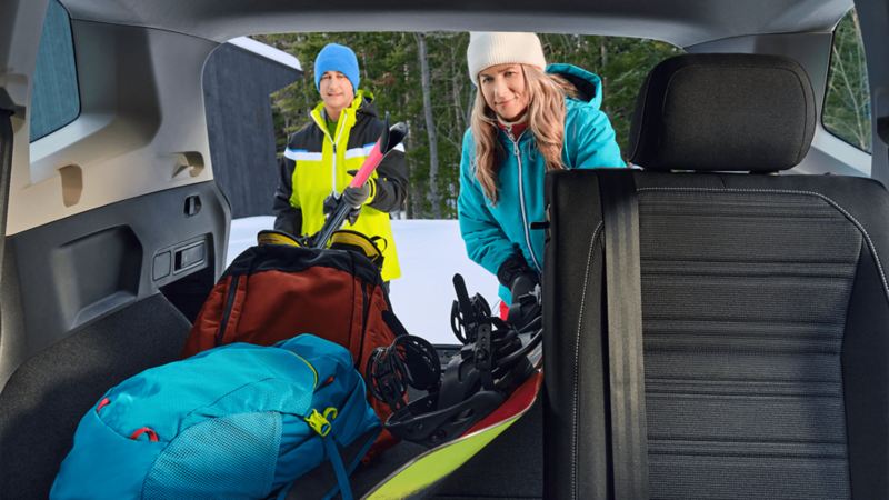 Une femme et un homme mettant l'équipement de ski dans le coffre du Volkswagen Tiguan 2023