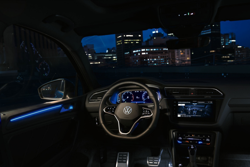 Cockpitansicht innen im VW Tiguan nachts, Farbdisplay zeigt Einstellungen des optionalen Ambientelichts, Innenraum blau beleuchtet.