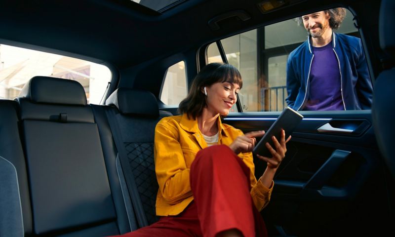 Vista interna di VW Tiguan, donna con tablet seduta sul sedile posteriore; L'hotspot Wi-Fi consente lo streaming e Internet all'interno del veicolo.