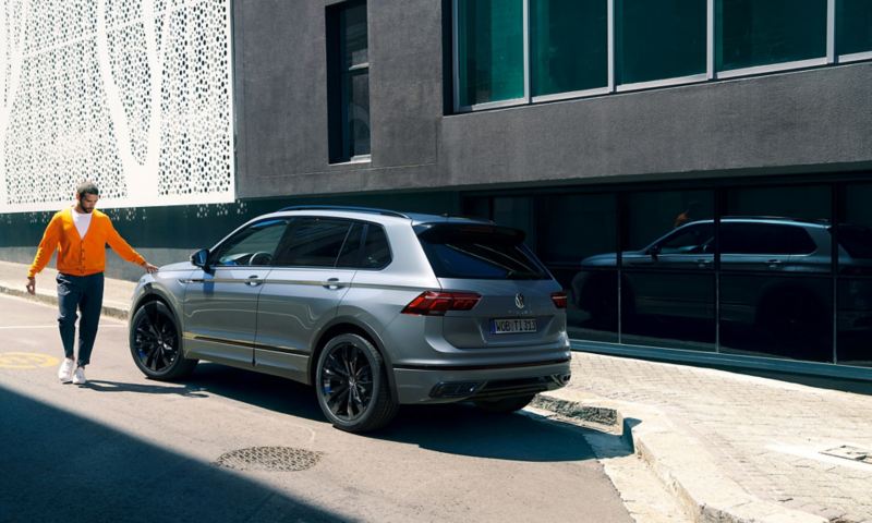 Un homme touche l'avant d'un Nouveau Tiguan R-Line "Black Style" du bout des doigts