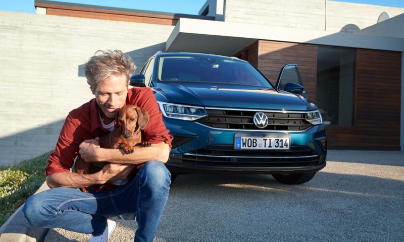 Homme avec teckel devant Volkswagen Tiguan