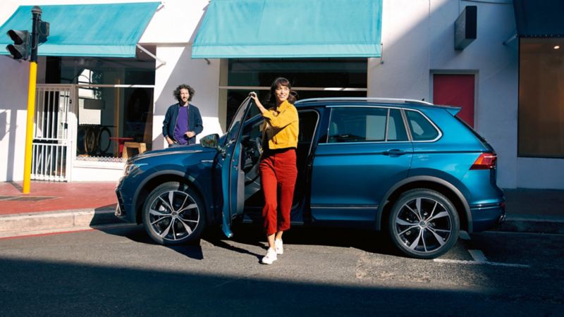 Frau steigt aus VW Tiguan in Blau – ClassicCredit.