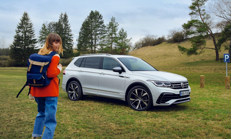 Biały Tiguan Allspace, a obok kobieta.