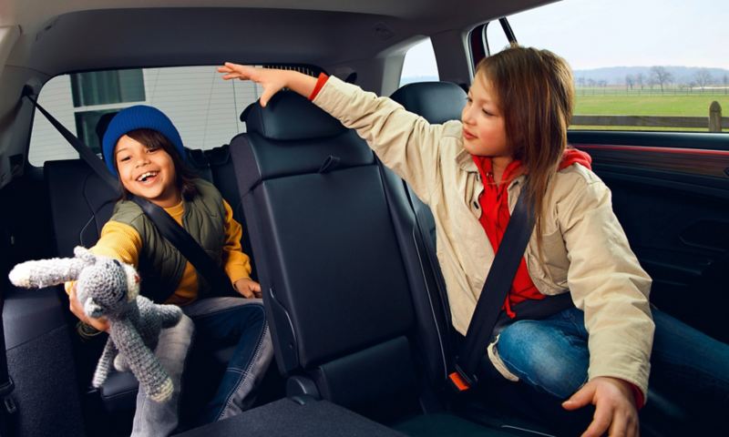Two children sit in the interior of a Tiguan Allspace Elegance: a girl in the second row of seats, a boy in the third row. 