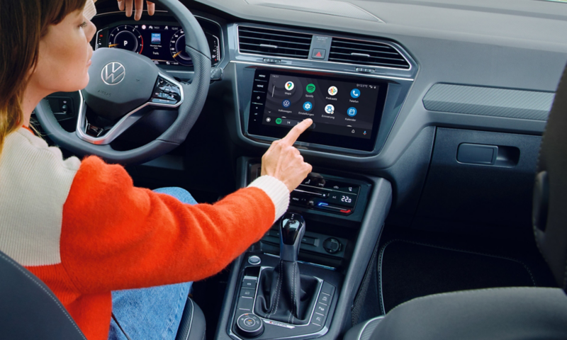 Vista del sistema di infotainment della Tiguan Allspace, raffigurazione delle app sul display. Una donna è seduta sul sedile del conducente. 
