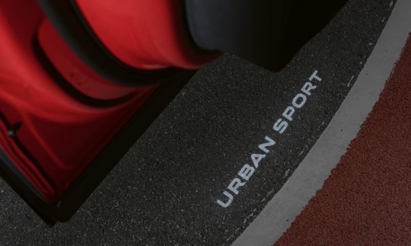 Logo projection of the lettering "URBAN SPORT" on the floor from the open driver's door of the Tiguan URBAN SPORT.