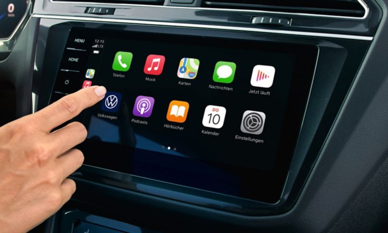Ansicht des Cockpits mit Farbdisplay. Im Display die Anzeige der Apps, eine Hand bedient die Touch-Fläche.