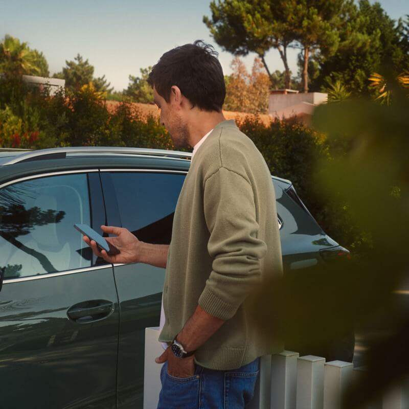 Osoba stojąca przed Volkswagenem z telefonem komórkowym w ręku
