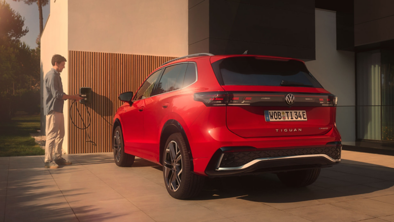 Situation de recharge du PHEV : vue arrière du VW Tiguan rouge garé devant une maison.