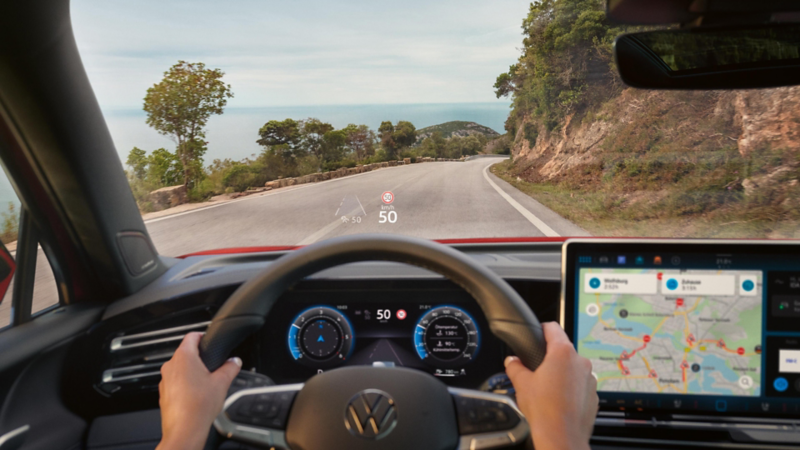 Iemand zit achter het stuur van een Volkswagen, het augmented reality head-updisplay wordt getoond op de voorruit