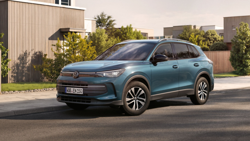 VW Tiguan ENERGY fährt auf Stadtstraße mit Gebäuden im Hintergrund.