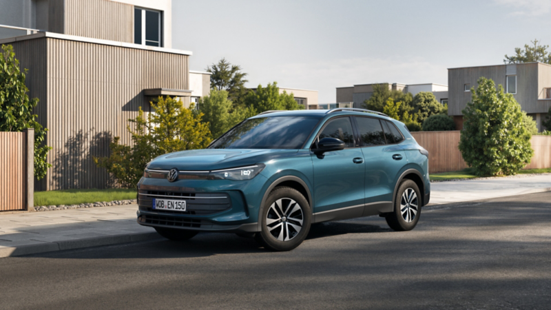 VW Tiguan ENERGY fährt auf Stadtstraße mit Gebäuden im Hintergrund.