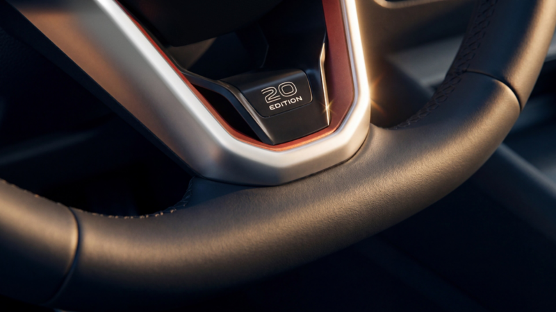 Detail view of the steering wheel spoke with Edition 20 lettering and a copper-red trim accent on the steering wheel of a VW Tiguan Edition 20.
