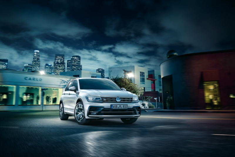 Un Tiguan R-Line sur l’asphalte, la nuit, au cœur de la ville.