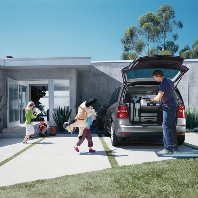 People loading luggage into the boot of a Volkswagen in preparation for a family road trip or holiday