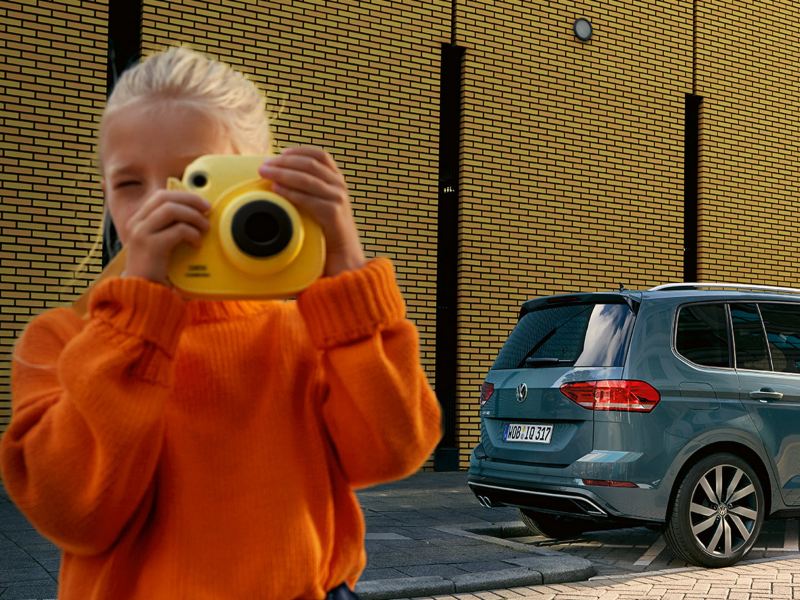 Mädchen mit Polaroidkamera vor einem VW