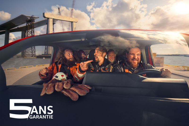 Plusieurs ouvriers du bâtiment sont assis dans un VW Transporter et plaisantent. Le logo de la garantie constructeur de 5 ans est également visible.