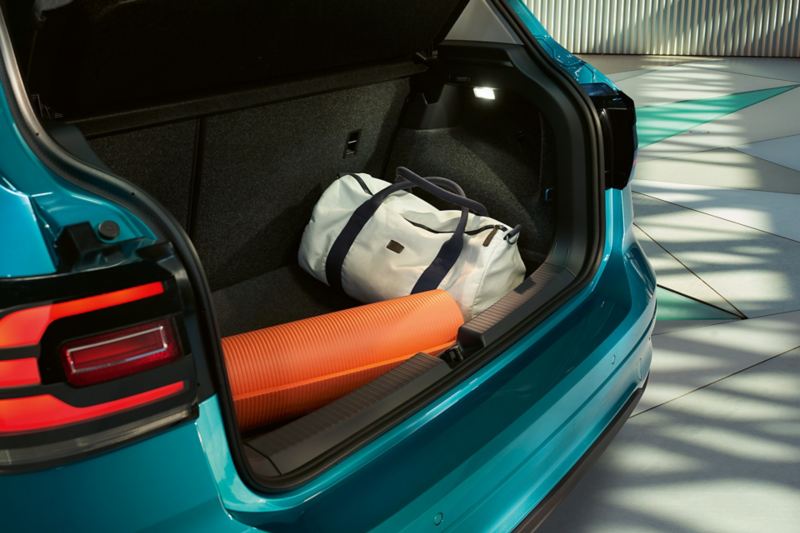 Ανοιχτός χώρος αποσκευών του Volkswagen T-Cross με τυλιγμένο στρώμα γυμναστικής και αθλητική τσάντα