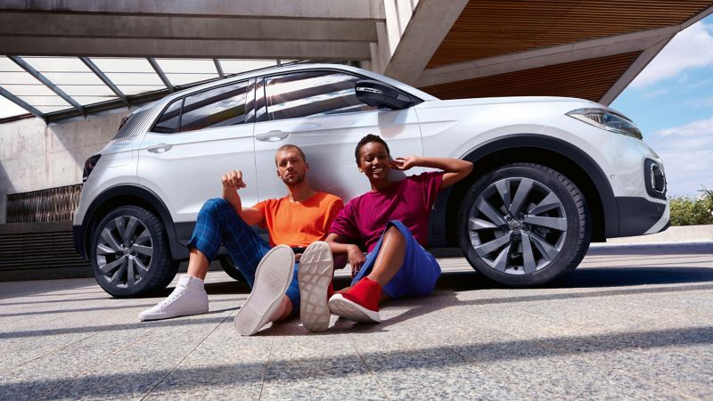 Due ragazzi seduti e appoggiati di spalle ad una vettura Volkswagen