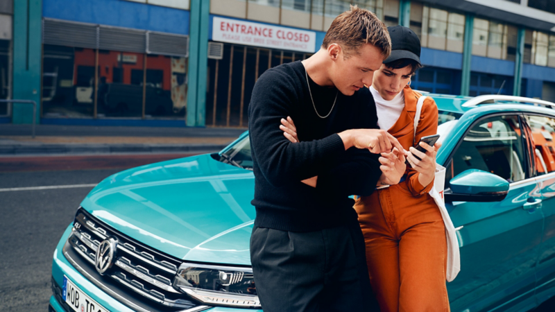 Two people lean on the bonnet of a green T-Cross