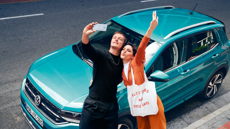 En mand og en kvinde tager et selfie foran en bil