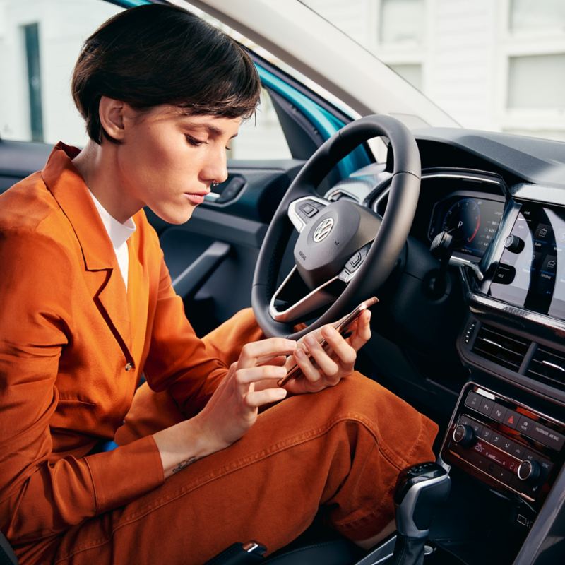 A woman holding a mobile phone in a VW vehicle
