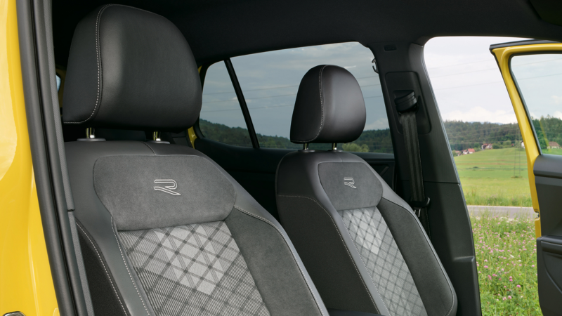 Close-up van het R-Line logo op de voorstoelen van een gele Volkswagen T-Cross