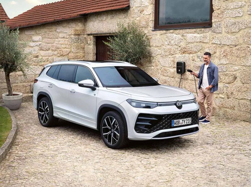 VW hybrid car charging at a charge point installed at a house. 