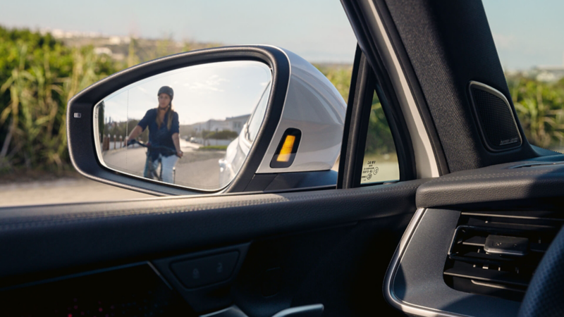 Close-up view of the Tayron's passenger side wing mirror showing a cyclist