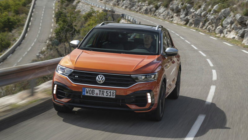 En orange t-roc kører i hårnålesving i alperne set forfra