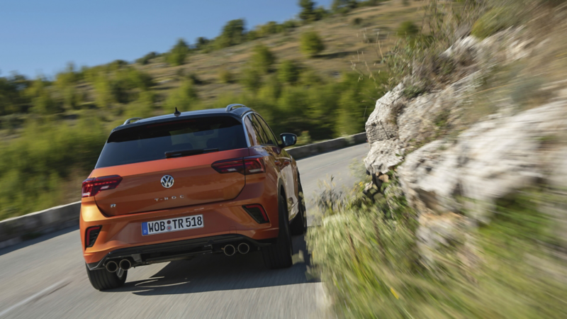 En orange t-roc kører i hårnålesving i alperne set bagfra