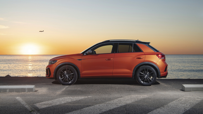 En orange t-roc holder parkeret ved vand kanten på en havn